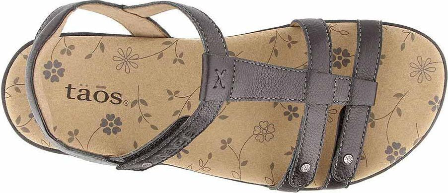 A brown sandal with multiple straps and a flower pattern on the insole, featuring the text "Taos".