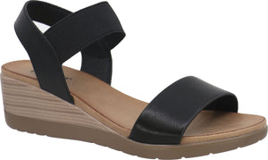 Black sandal with elastic ankle strap and low wedge heel.