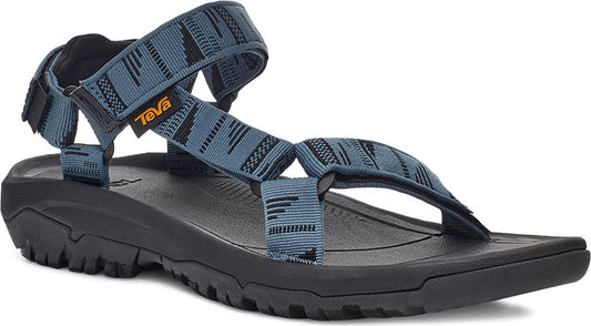 A blue sandal with black soles and straps with a geometric pattern.