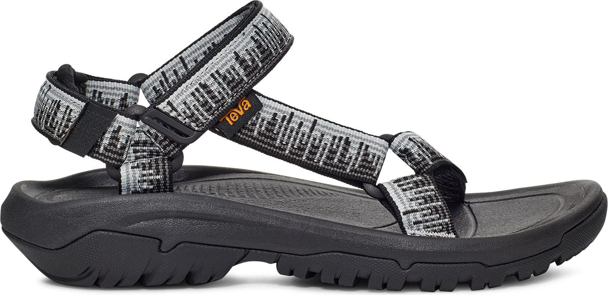 A sandal with black patterned gray straps and a chunky black sole.