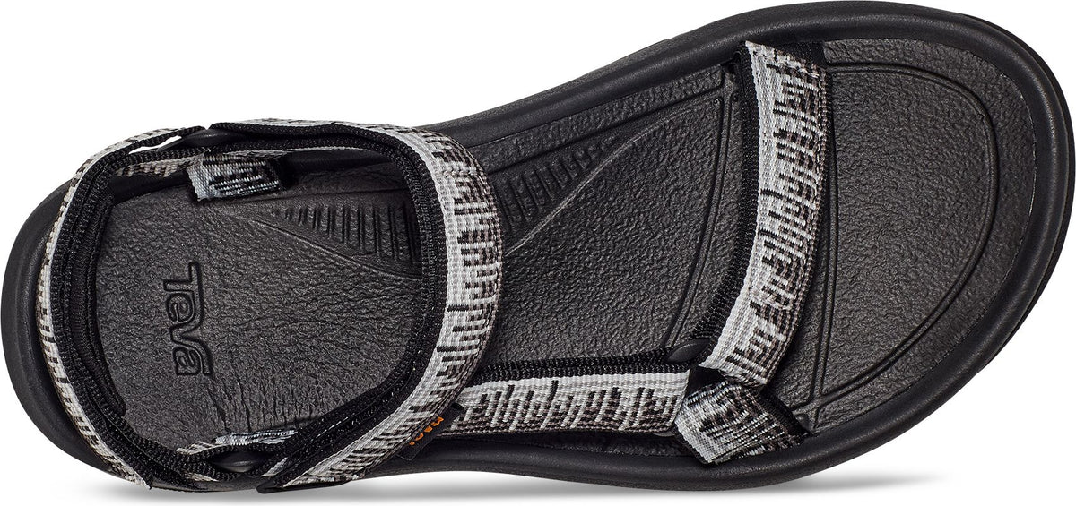 The bottom view of a sandal with black sole and patterned straps.