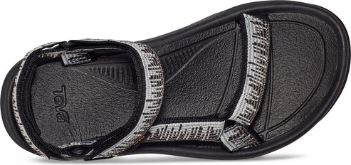 The bottom view of a sandal with black sole and patterned straps.