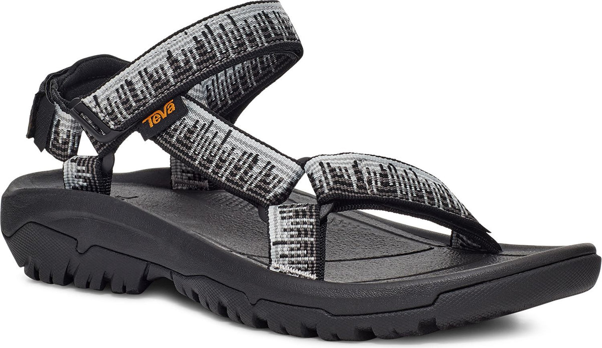 A sandal with black soles and gray-white patterned straps.