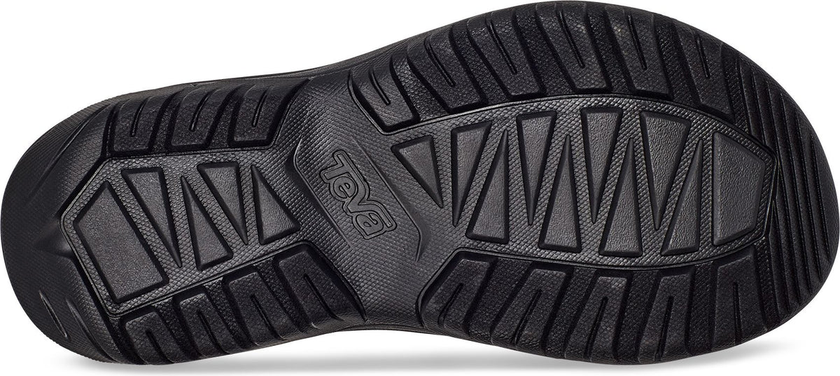 Bottom view of a black shoe showcasing a complex tread pattern of triangles and rectangles.