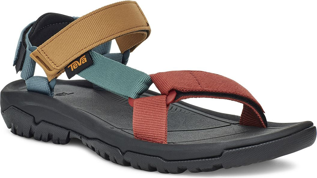 An angled, close-up of a black sandal with rust-colored, khaki, teal, and navy straps, and a "TEVA" tag.