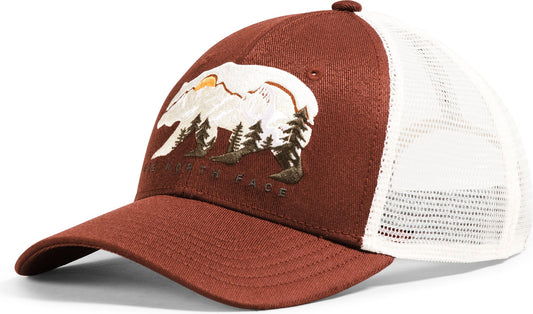 A brown trucker cap with a white mesh back and an embroidered design of a bear, trees, and a mountain with a rising sun.