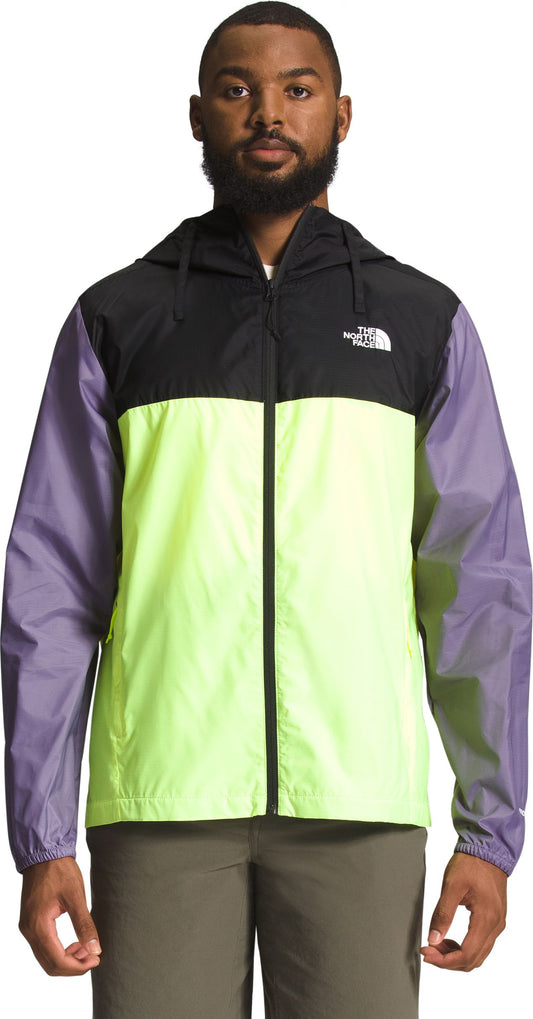 A man wearing a black, yellow, and lavender rain jacket with a hood and a zipper.