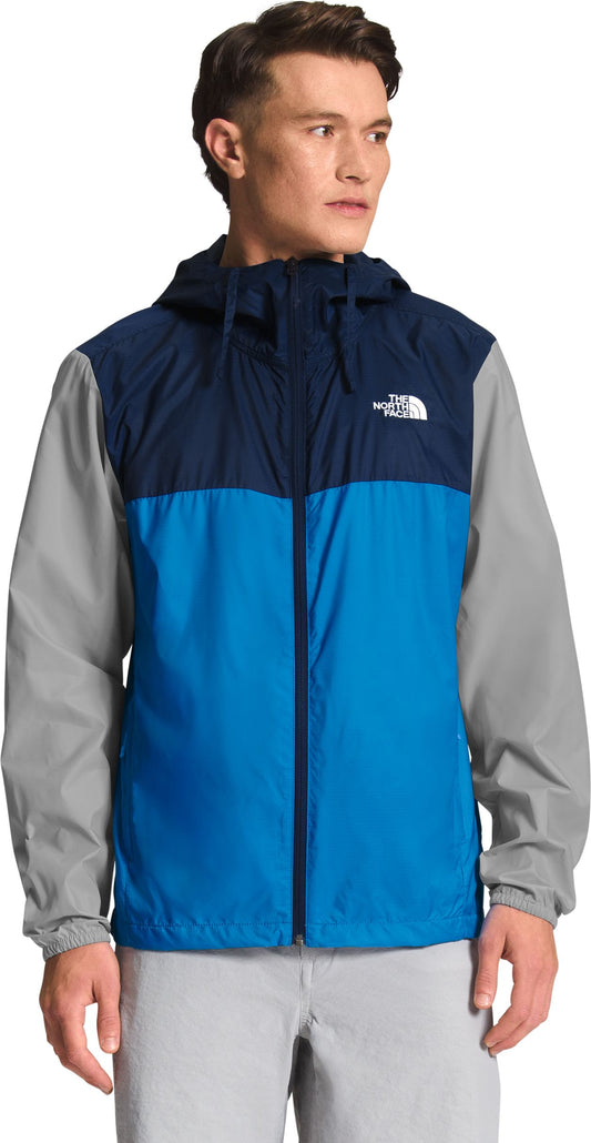 Man wearing color-blocked blue, navy and gray hooded jacket.