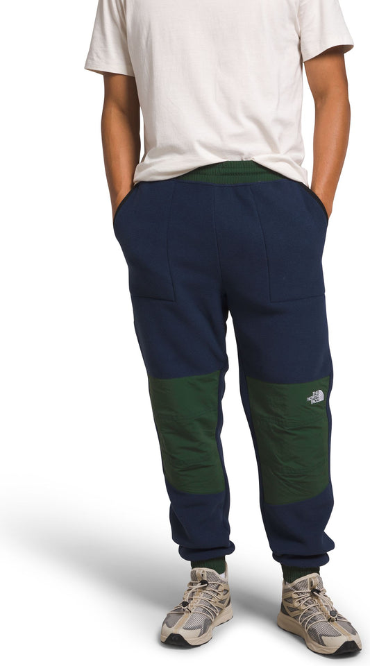 A person wearing blue and green sweatpants with an elastic waistband and ankle cuffs.