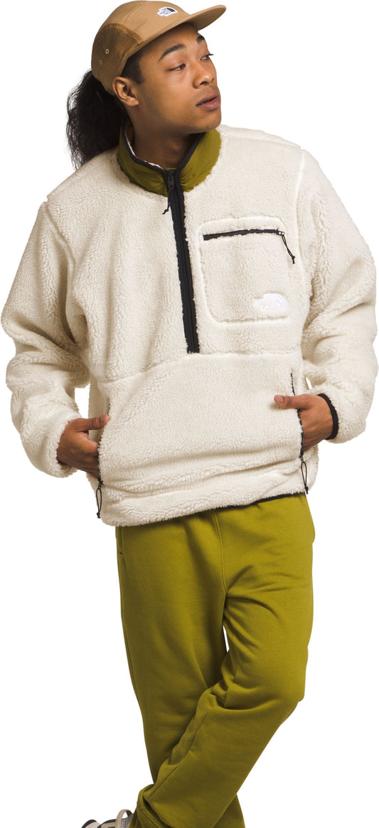 A man in a tan hat, white fleece pullover and olive green pants poses.