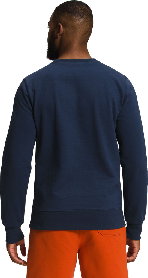 Man in navy crew neck sweatshirt and orange shorts, back view.