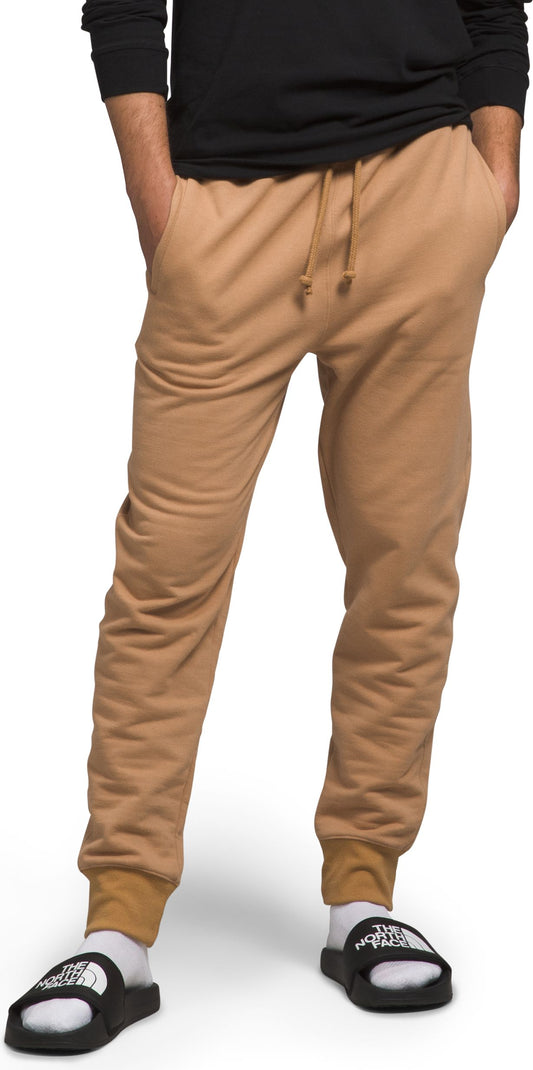 A person wearing tan sweatpants and black sandals with white socks.