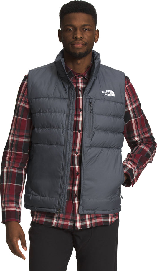 Man wearing a dark gray puffer vest over a red plaid shirt.