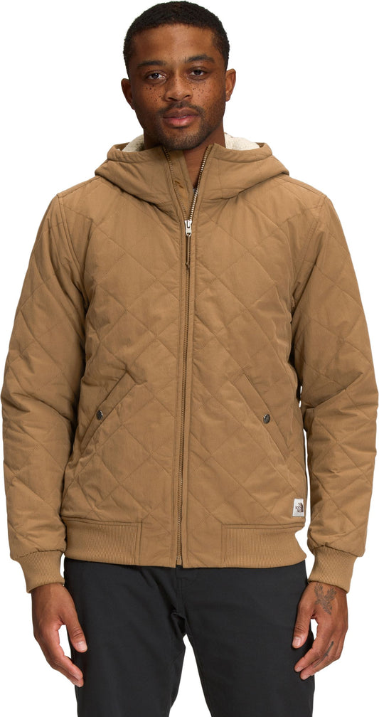 A man in a brown quilted hooded jacket with a zipper.