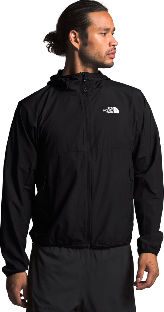 A man wears a black zip-up jacket with a hood and logo.