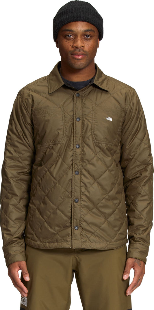 A man wearing a quilted, button-down shirt and beanie.