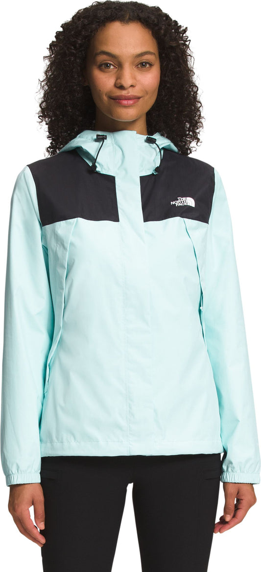 A woman wearing a mint green and black rain jacket with a hood.