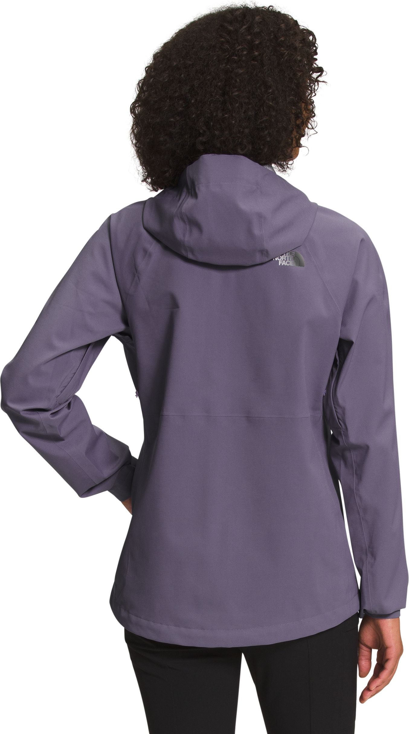 Back view of a woman wearing a purple hooded jacket with a logo on the upper back.