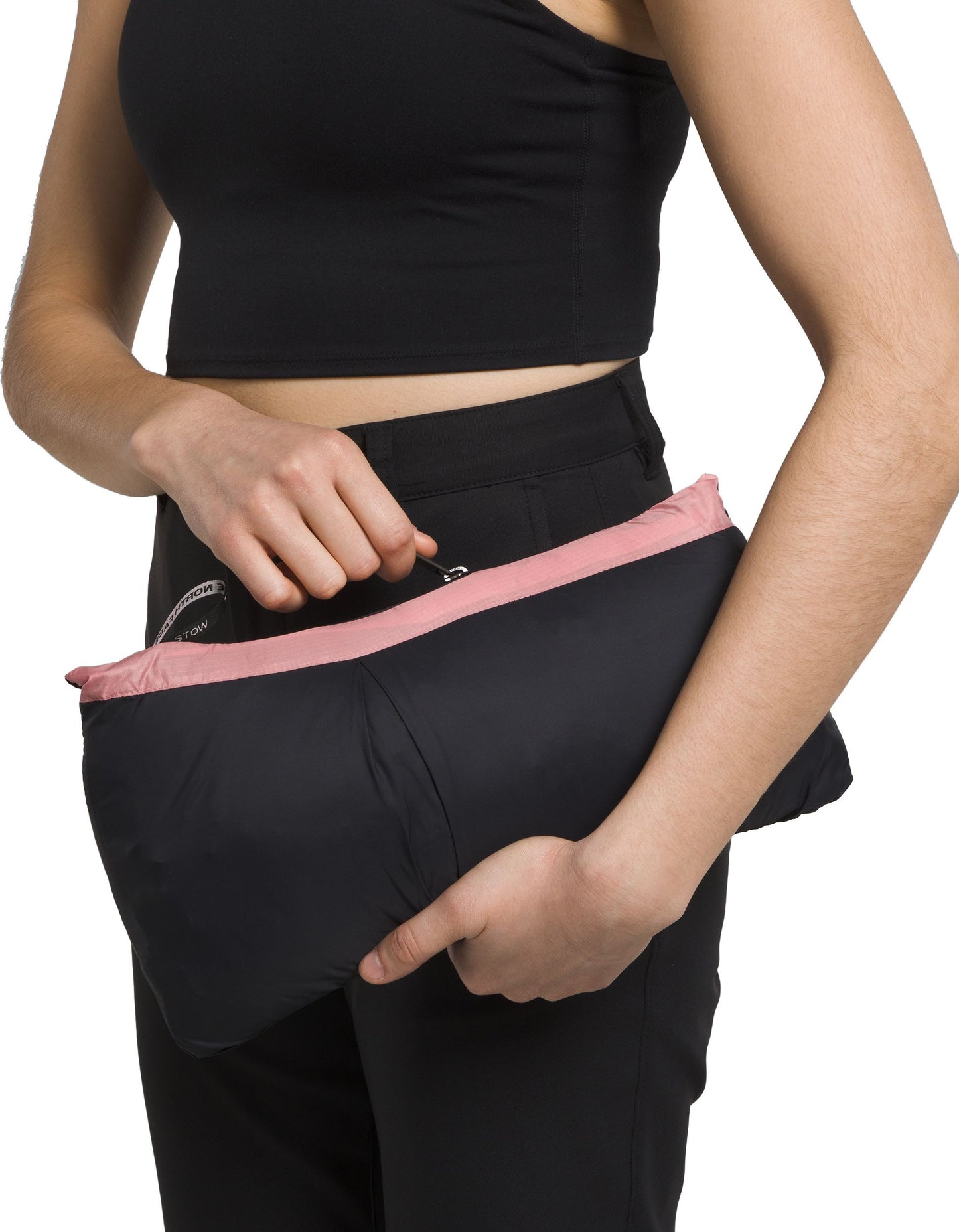 Person in black holding folded black jacket with pink lining.