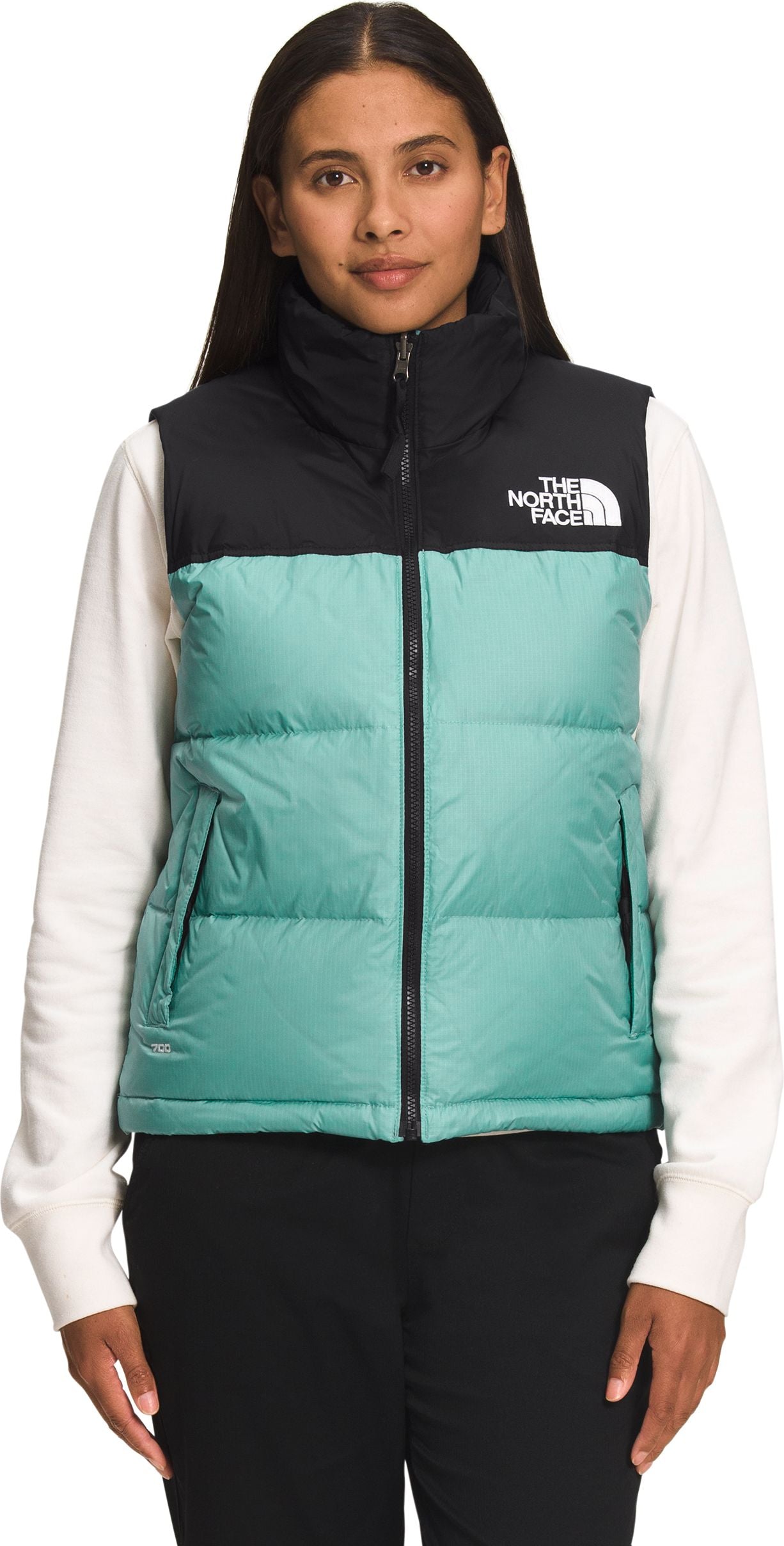A model wearing a two-toned vest with black at the top and mint green in the midsection. The text "THE NORTH FACE" is on the right side.