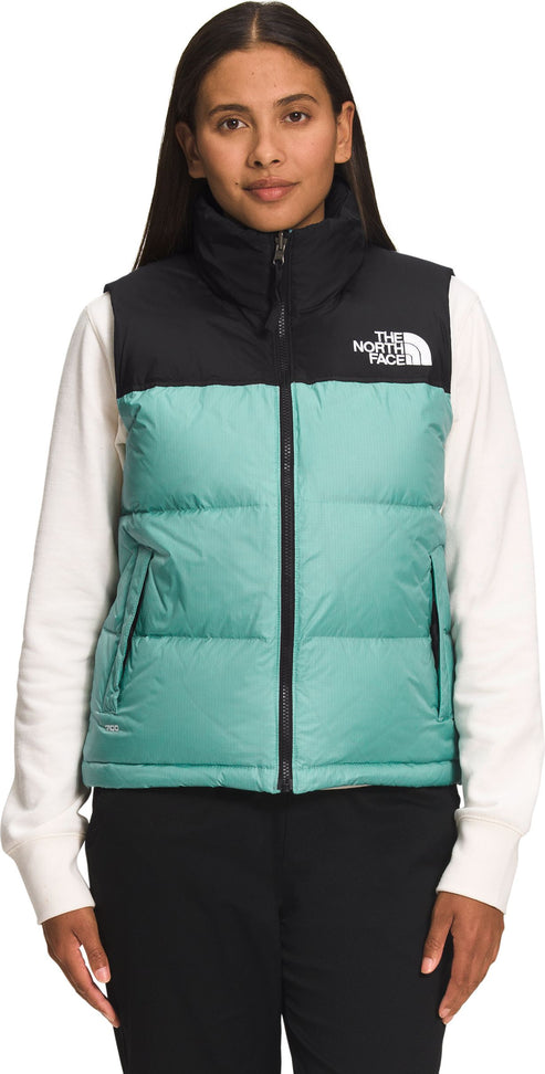A model wearing a two-toned vest with black at the top and mint green in the midsection. The text "THE NORTH FACE" is on the right side.