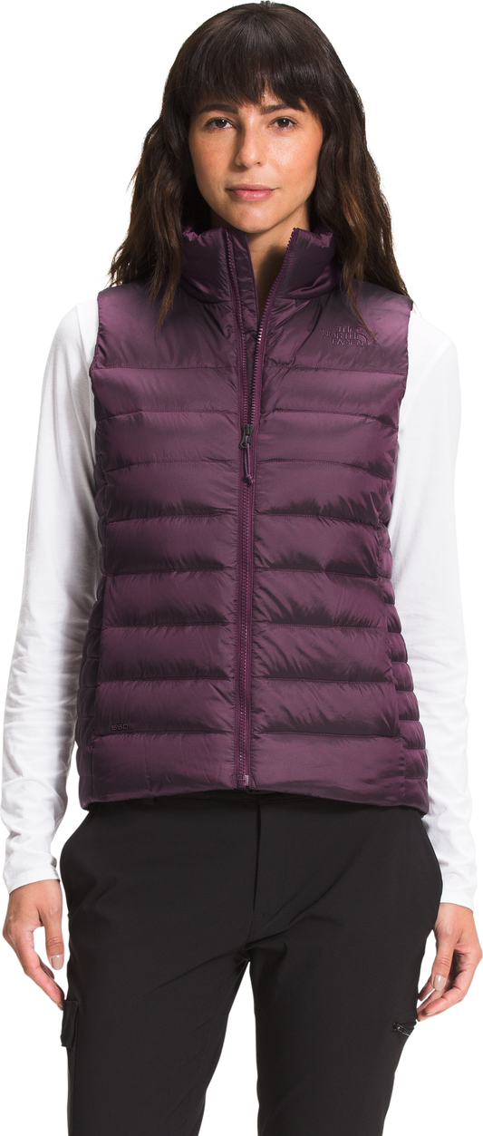 A woman wears a purple puffer vest over a white long-sleeve shirt and black pants.