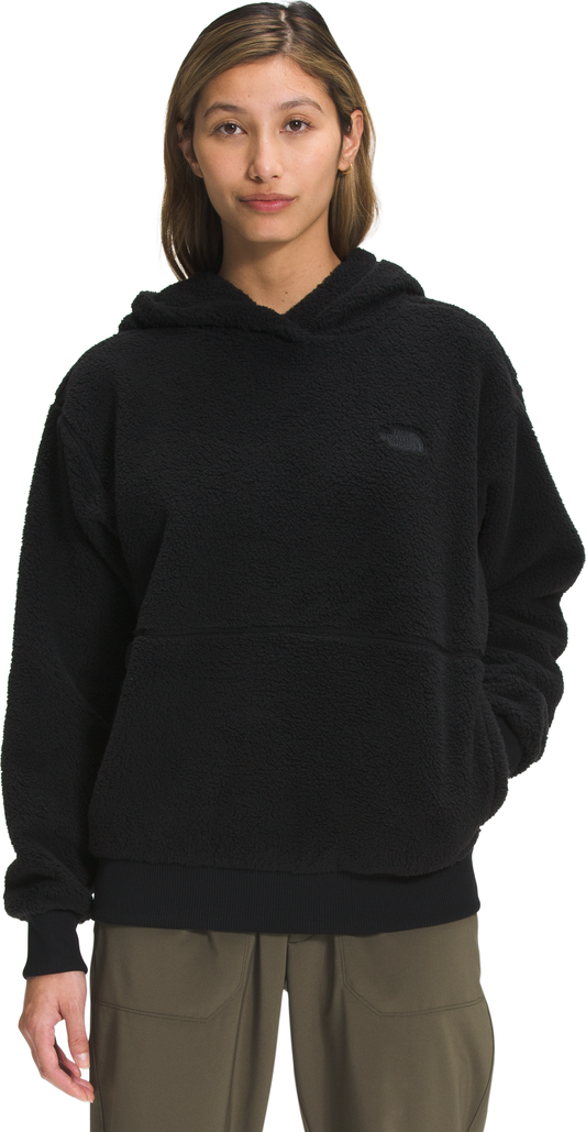 A woman wears a long-sleeved black hoodie with a front pocket.