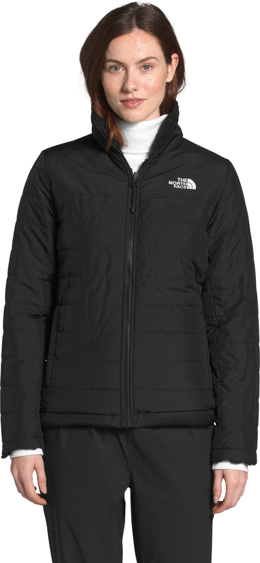 A person wearing a black padded jacket over a white turtleneck.