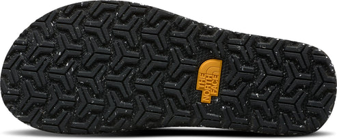 The textured black sole of a shoe with a repeating triangular pattern and a tan logo.
