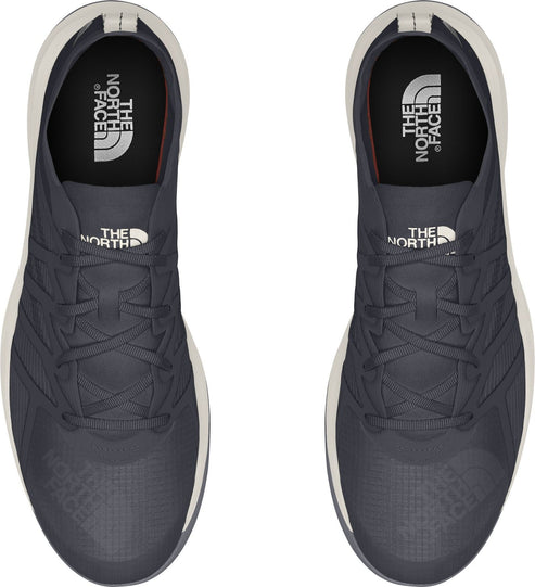 Overhead view of two dark gray athletic shoes with white soles and white laces.
