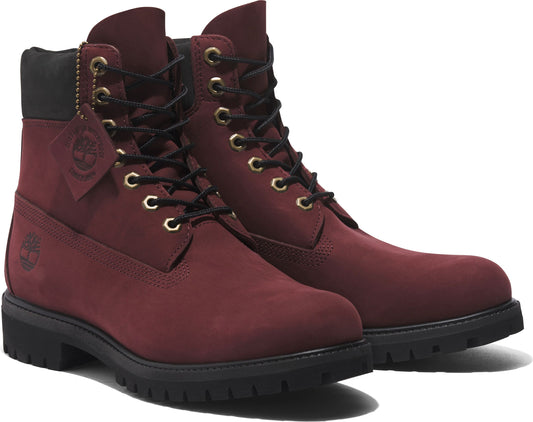 A pair of maroon leather boots with black soles and gold eyelets.