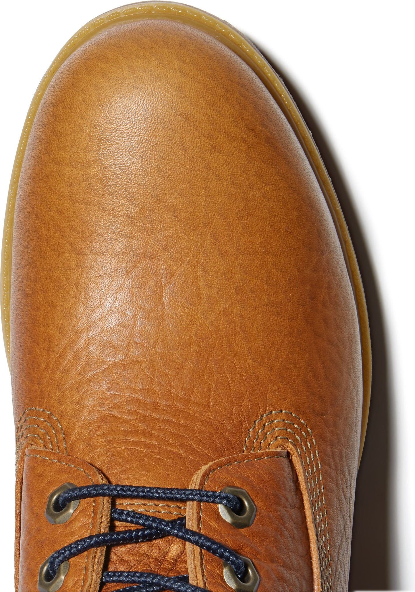 Top-down view of a wheat-colored leather boot featuring dark blue laces with metal eyelets.