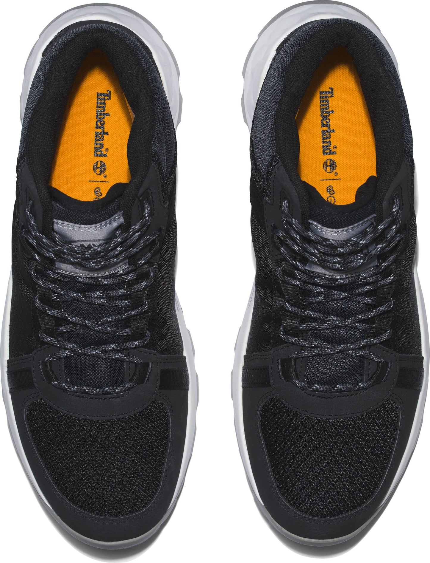 Overhead view of a pair of black sneakers with white soles and orange insoles.