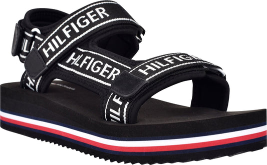 Black sandal with 'HILFIGER' printed white straps and a red, white and blue stripe on the sole.