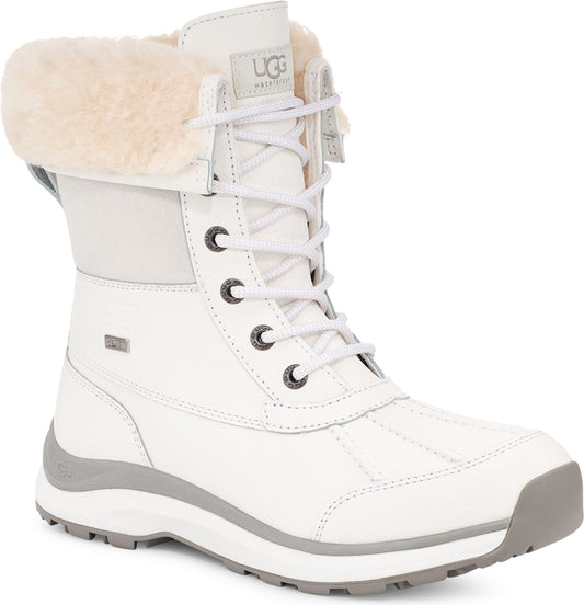White lace-up boot with fur trim and gray soles, UGG logo visible on tongue.
