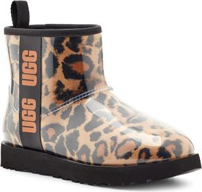 Ankle-high boot featuring a brown and black leopard print design under a clear waterproof-looking material with the word UGG printed vertically in brown on a black band.
