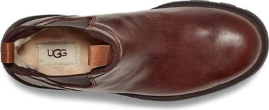 A brown leather boot with a pull tab and visible UGG brand on the inner sole.