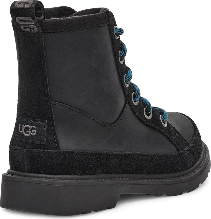 Black UGG boot with suede heel and toe box, blue shoelaces, and silver metal eyelets.