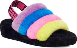 A fluffy slipper with black base and a rainbow-colored faux fur upper consisting of purple, blue, pink, and yellow stripes; the slipper has a pink elastic strap with black lettering.