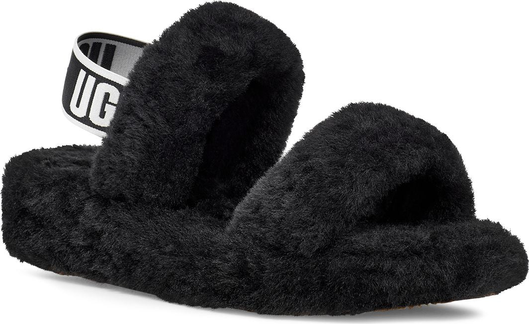 Black, fuzzy slip-on sandal with a white strap reading "UGG".