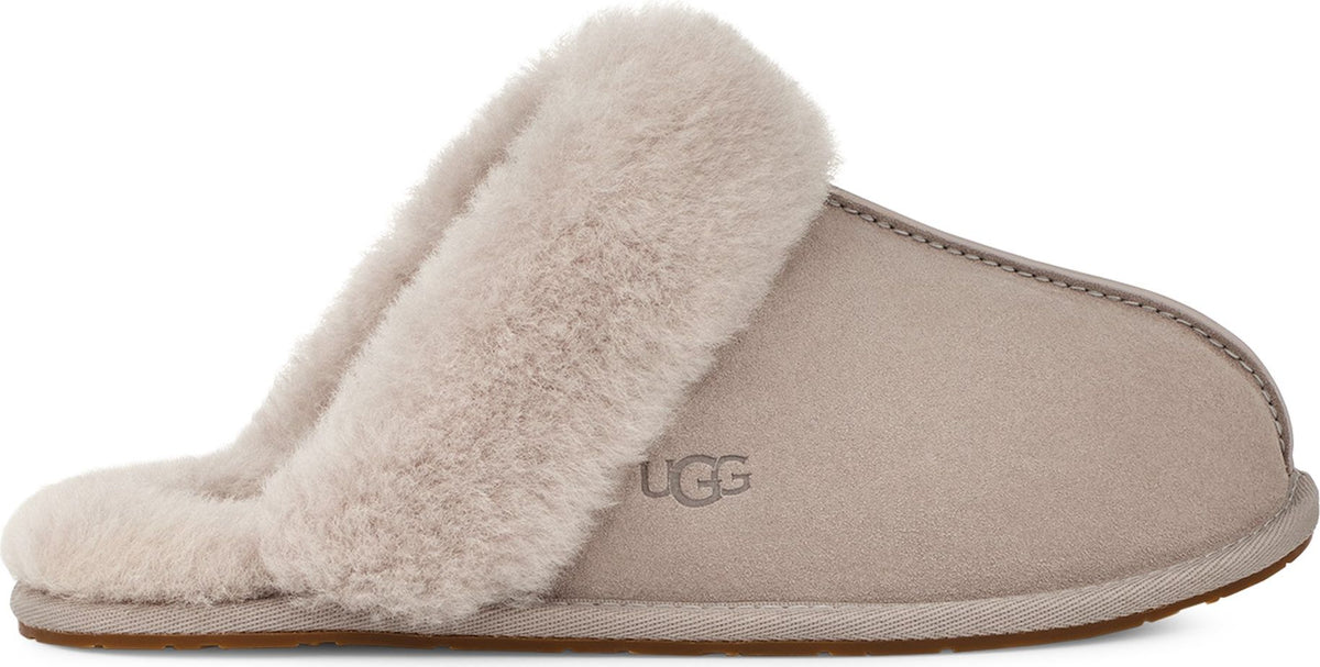 Beige slipper with faux fur trim and rubber sole, UGG logo visible.