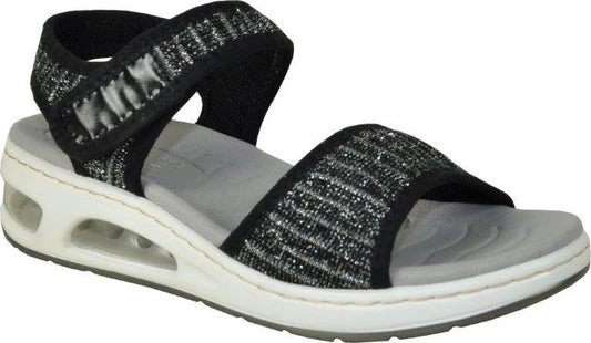 A woman's sandal with black and silver glittery straps, adjustable velcro closure, and a white sole with air pockets.