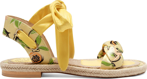 Flat sandal with a jute-style sole and yellow straps with fruit print, one tied around the ankle.