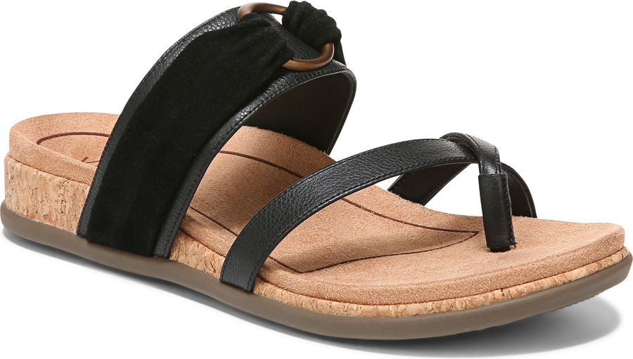 A women's sandal with a black toe thong strap and a wide black strap held by a bronze-colored ring, on a brown sole with a cork midsole.