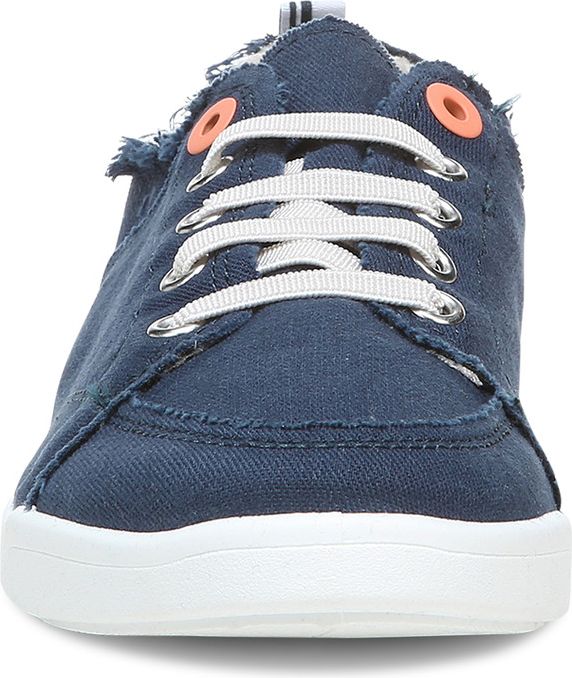 Close-up of blue canvas sneaker with white laces and white sole, featuring decorative frayed edges.